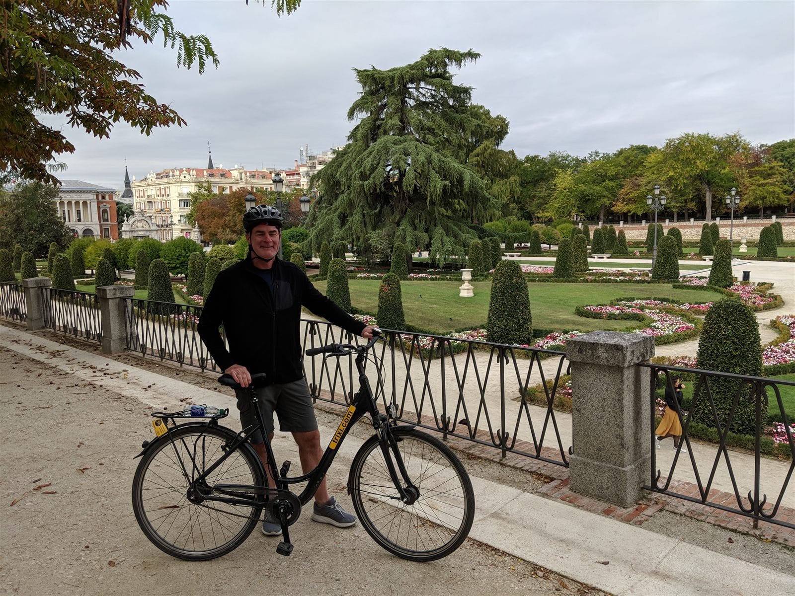 Cyclist with a rental bike in the formal gardens of El Retiro