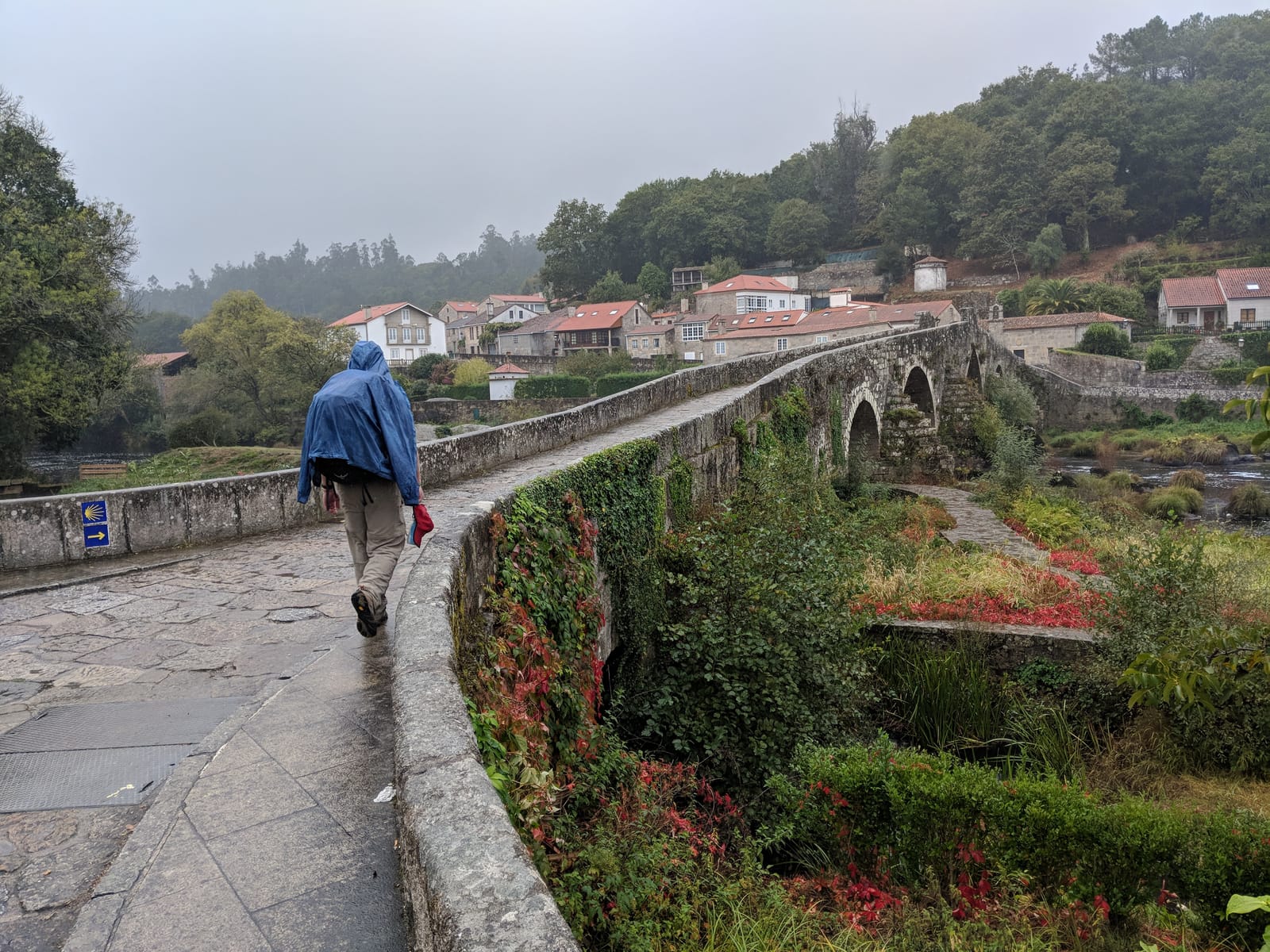 Doug in a rain jacket crossing the medieval Ponte Maceira bridge in the rain