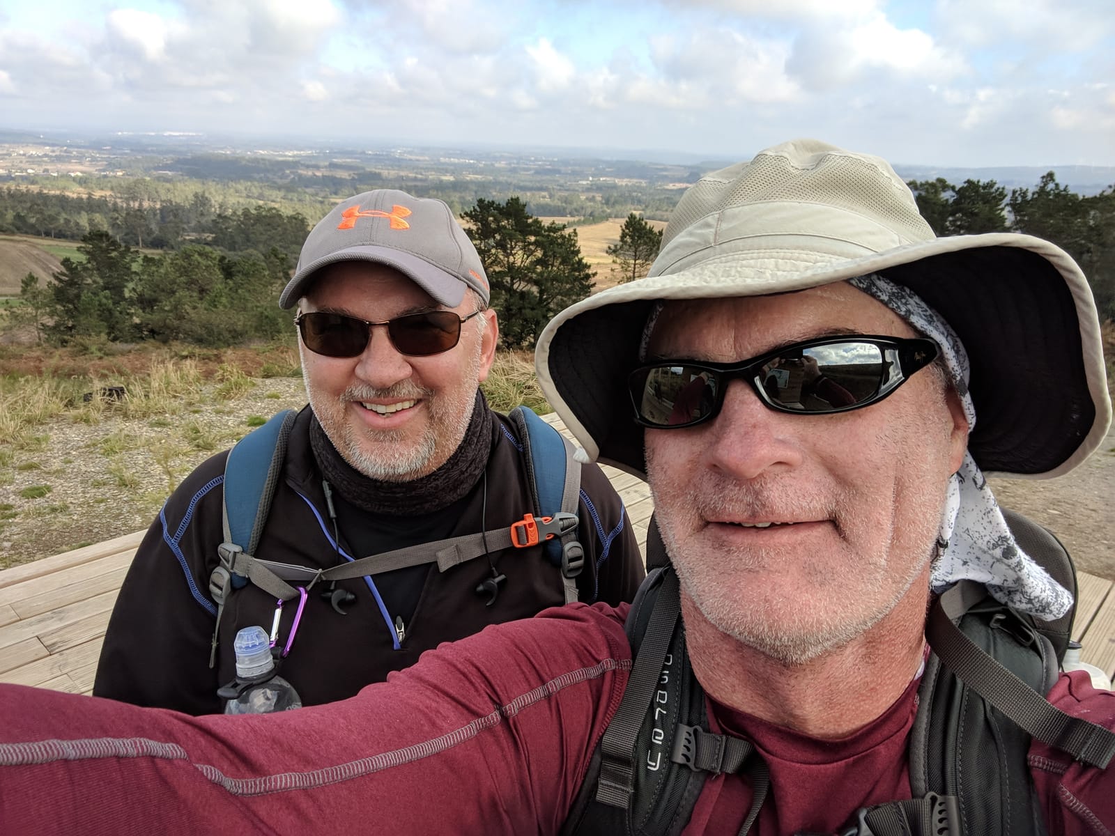 Mike and Doug taking a selfie at a hilltop viewpoint over the countryside