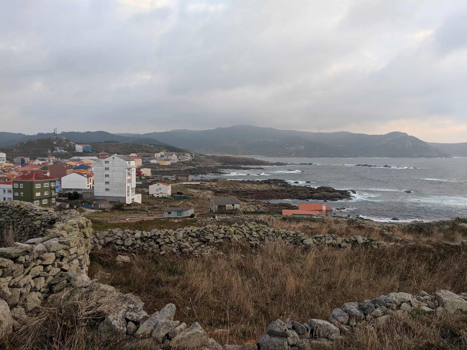 View over Muxía's houses and the rocky Atlantic coast from old stone walls