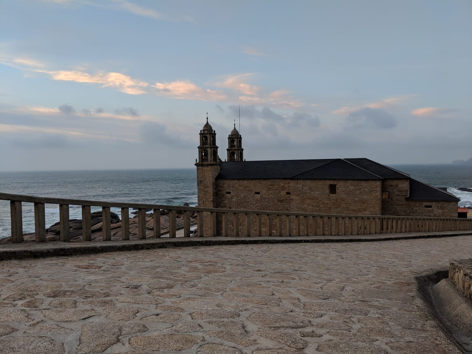 The Santuario da Virxe da Barca, a Baroque stone church with twin bell towers, on the rocky Muxía coast