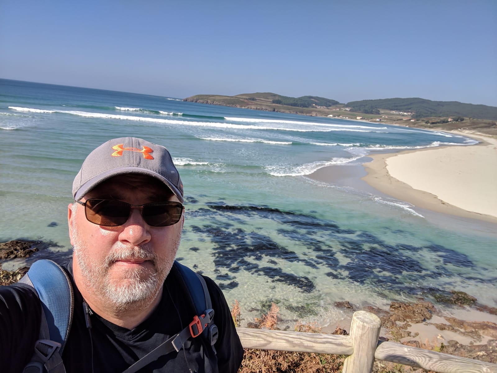 Mike in a cap and sunglasses taking a selfie above the turquoise beach