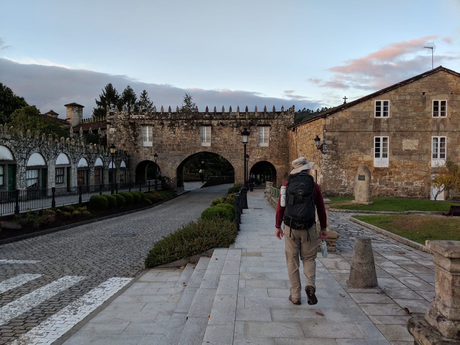 Doug walking out of Negreira at dawn past a crenellated stone pazo