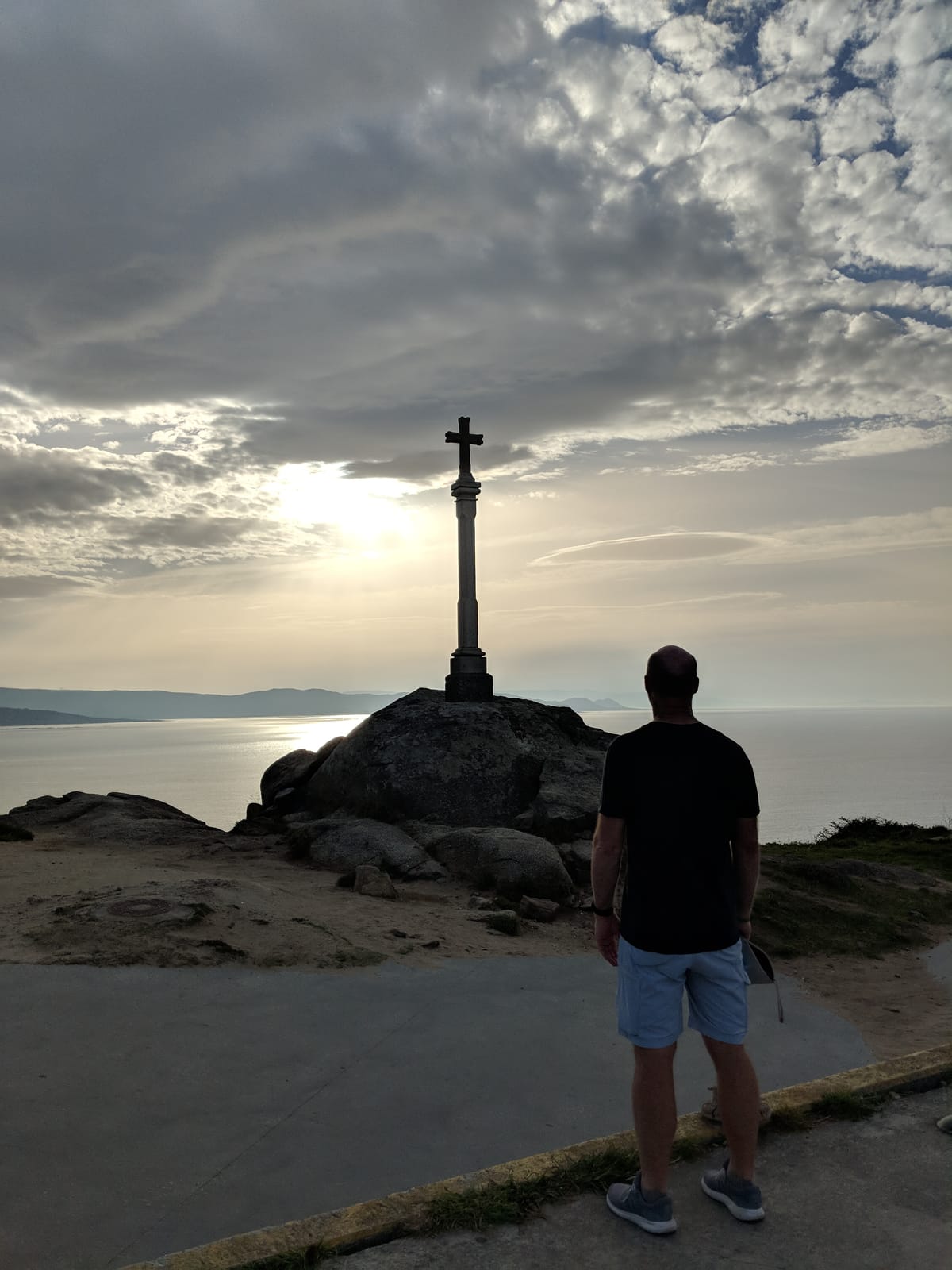 Doug looking out to sea by a stone cross at the cape