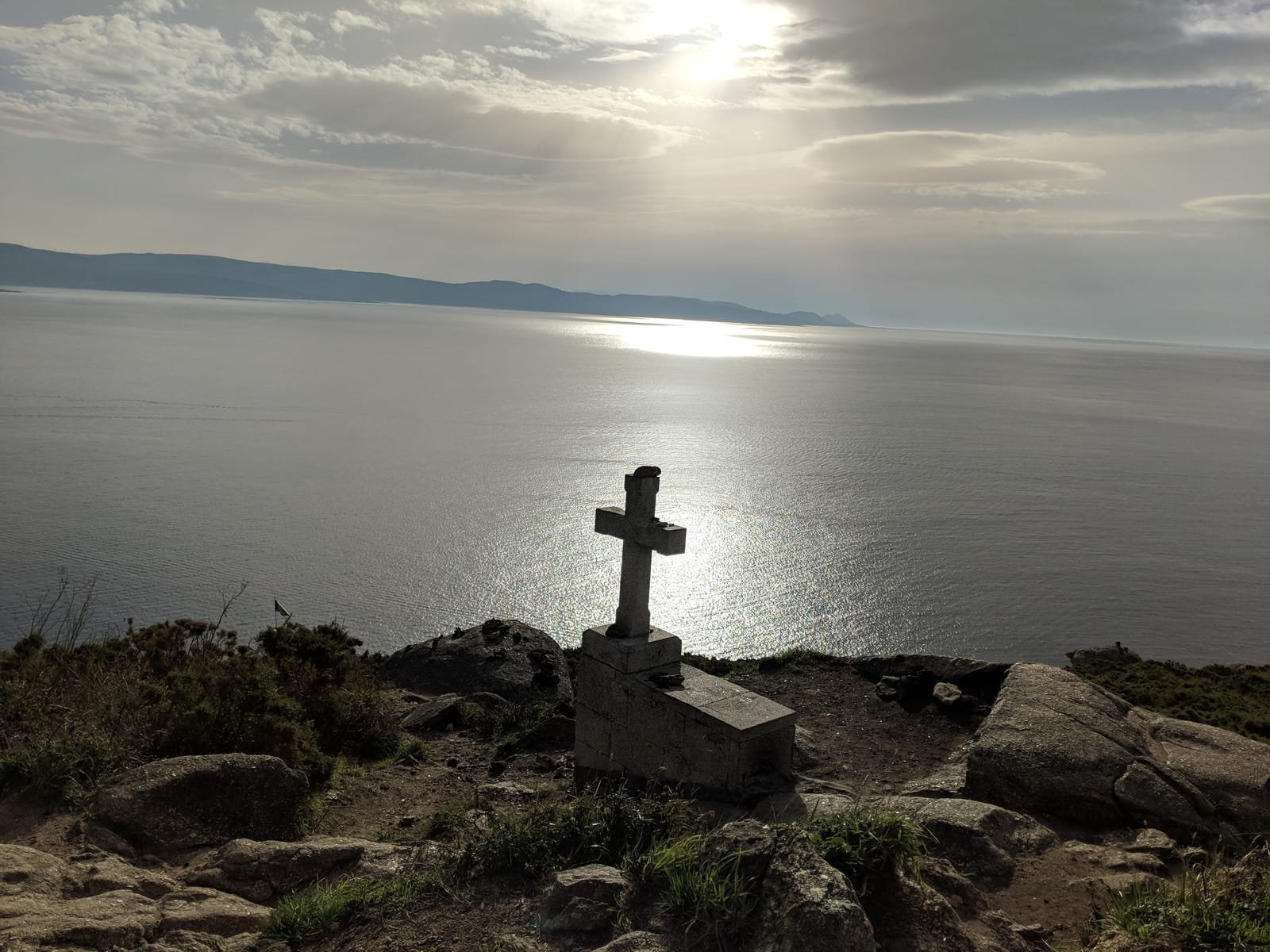 Stone cross on the clifftop above a sunlit sea