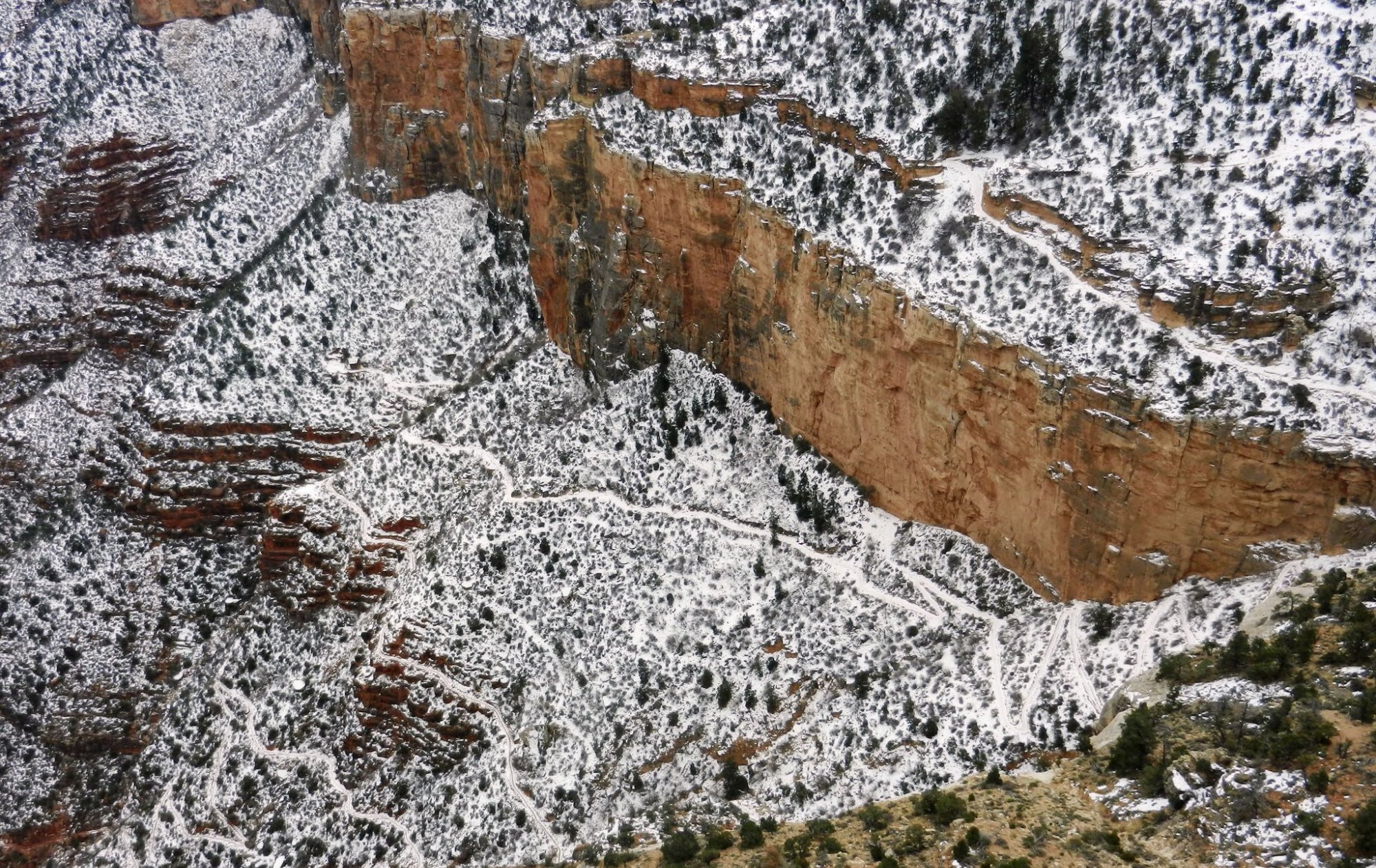 Snowy canyon rim with switchback trail visible