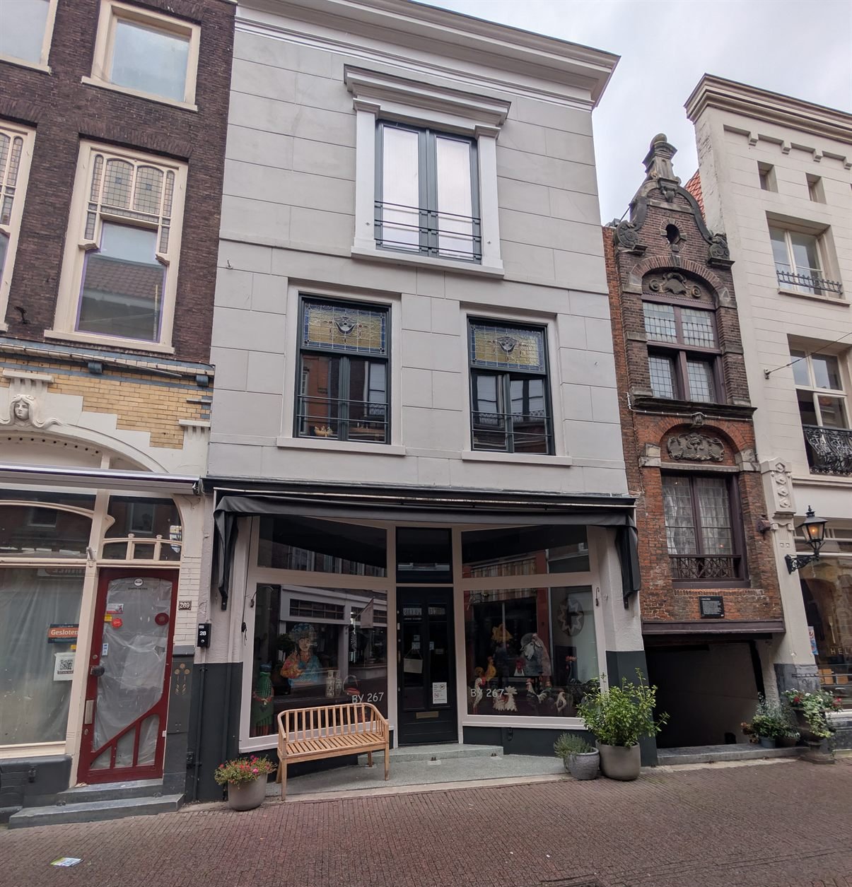 Voorstraat 267, Dordrecht, from the street: a three-storey house with a pale plastered facade, a shop on the ground floor with a black awning and a central door between two display windows