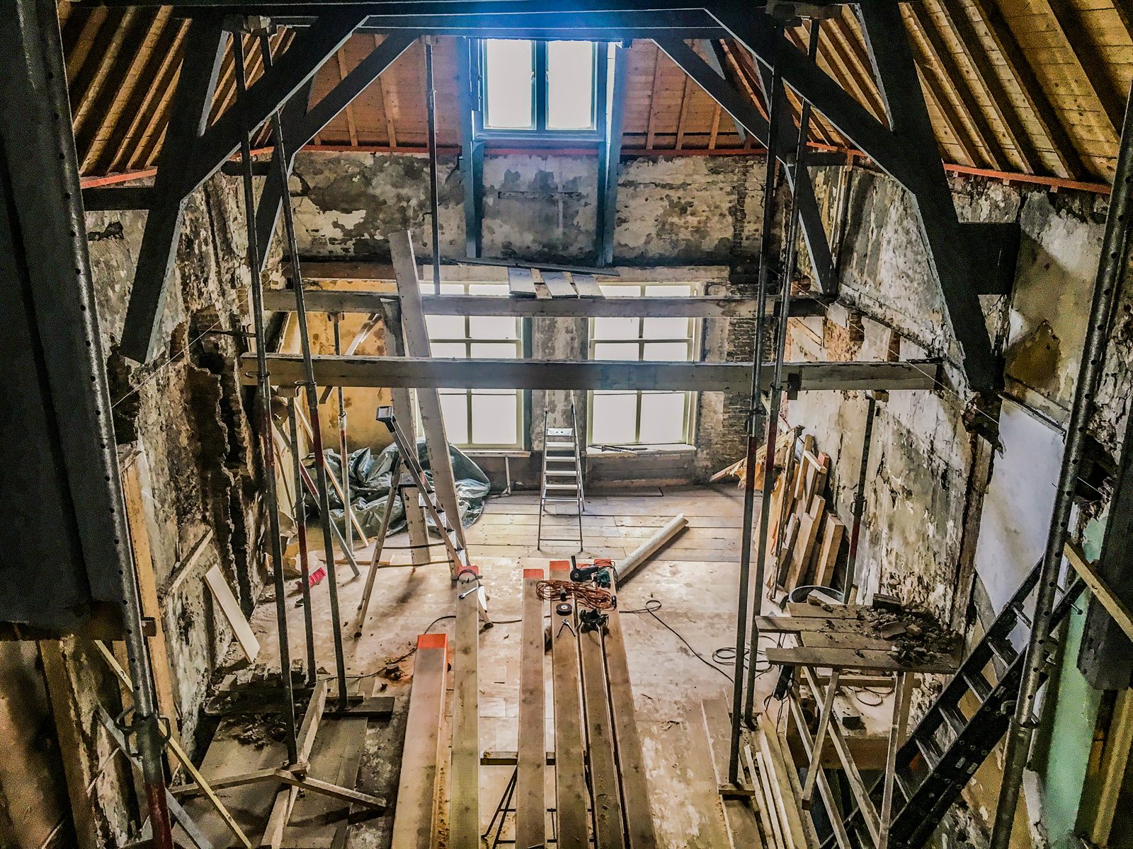 The interior of 267 during renovation: stripped to bare brick and plaster, floors removed, steel props holding the walls, the roof open to its rafters