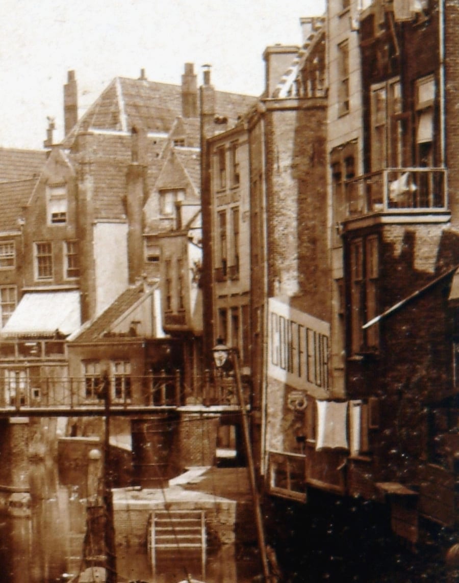 Close view of the same photograph: a tall narrow house whose side wall carries a painted sign reading COIFFEUR, above the end of the alley and the steps down to the water