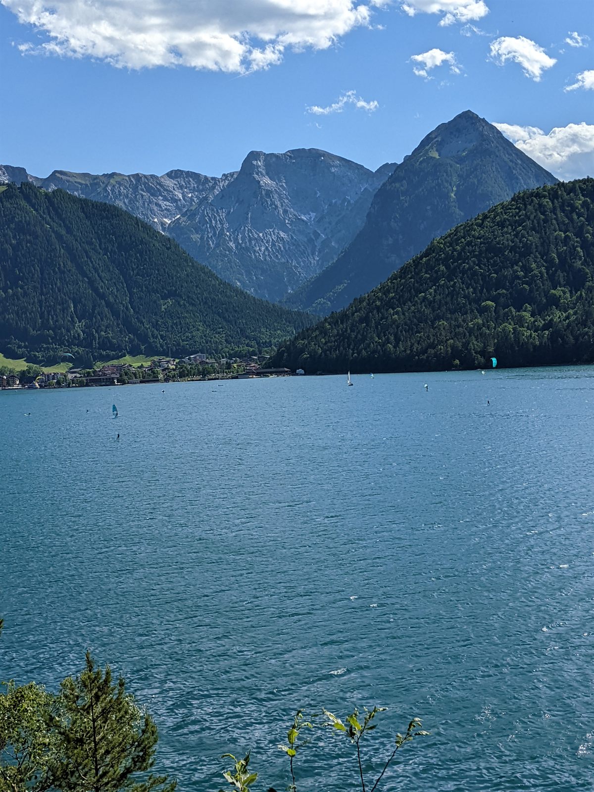 Windsurfers and kitesurfers on the Achensee below sharp Karwendel peaks