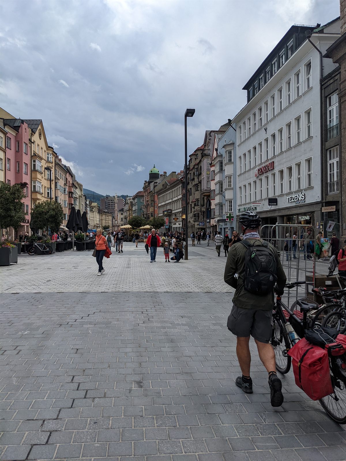 Innsbruck's old-town pedestrian street lined with colorful facades, Doug walking his loaded bike among the crowd