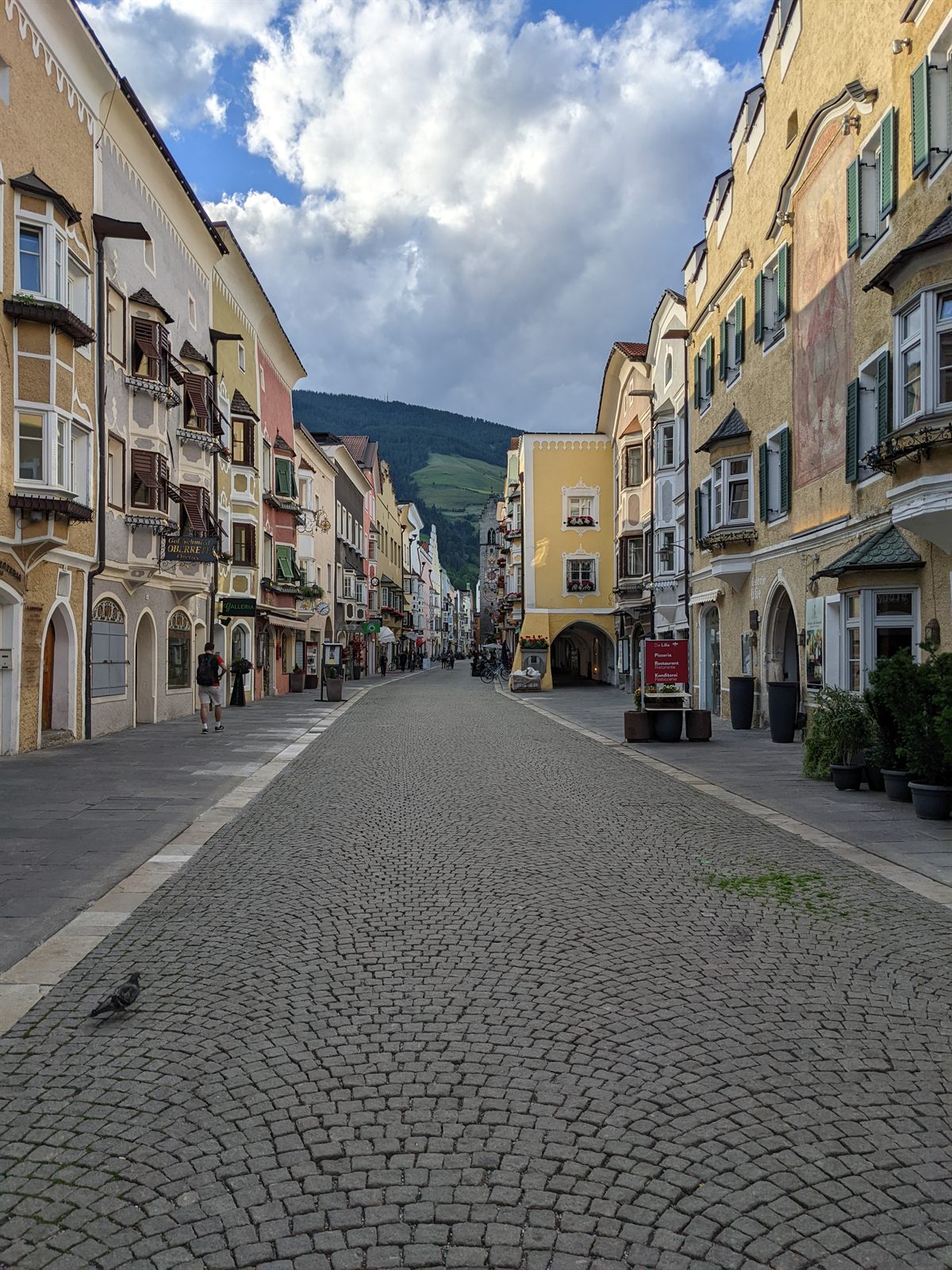 Vipiteno's cobbled old-town main street lined with colorful arcaded Tyrolean houses in the evening light