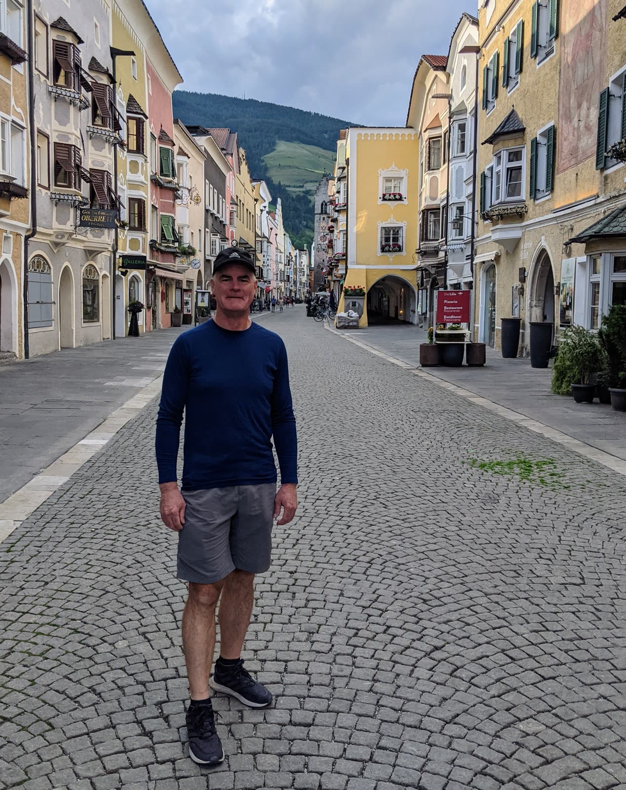 Doug standing on Vipiteno's cobbled main street lined with painted Tyrolean facades in the evening